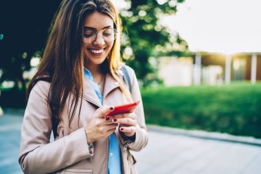 Ücret tahsil online yapma gözlük neşeli hippi kız modern smartphone stolling açık havada üzerinde yüklü bankacılık uygulaması kullanıyor. Kopyalama alanı alanı reklam metin iletinizi için
