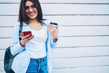 Yarım uzunluk portre neşeli genç kadının telefon ayakta beyaz arka plan üzerinde posta kontrol arkadaşım mesaj söyleyeceğiiçin çok mutlu. Smartphone uygulama kullanarak gülümseyen kadın blogger