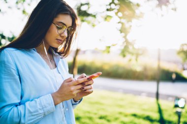 Online sohbet ve web sitesi ile müzik çalma listesi açık havada publisity alan yakın duran dan modern earnphones cep telefonu dinleme şarkıları indirmek için tarama Pencive kadın hipster