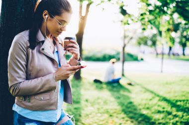 Şık kıyafet favoutive şarkıda telefona bağlı ve sonraki ses çalma listesi daimi kahve kopyalama alanı alanı parkı ile seçme kulaklık sesinin tadını genç hipster kadın giyinmiş