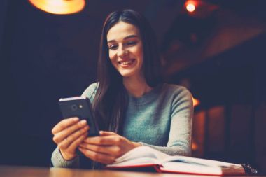 Neşeli blogger operatör dijital smartphone cep telefonu ile yer coworking yılında açılan edebiyat kitabı, oturmak iyi haber ile alınan sms mesajı okuma. Cep üzerinde online alışveriş yaparken pozitif öğrenci