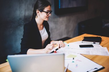 Çizimler ve modern bilgisayar aygıt ile ahşap masaüstü oturan ve yeni bir proje üzerinde çalışırken gözlük genç profesyonel mimar. Dizüstü üniversitede öğrenim gözlük yetenekli öğrenci