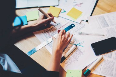 Mimar kırmızı işaret ve çizim için çizgiler kroki bina ile Resim kırpılmış. Kadınların elleri masaüstünde farklı aletleri ve telefon oturma planı işaretleri yapma Üstten Görünüm