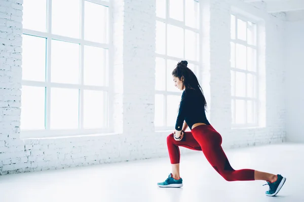 坚定的女性在时髦的主动磨损工作的腿伸展和力量在锻炼期间 运动员做锻炼为下身体在健身目标和健康生活方式的刺激下在健身房 — 图库照片