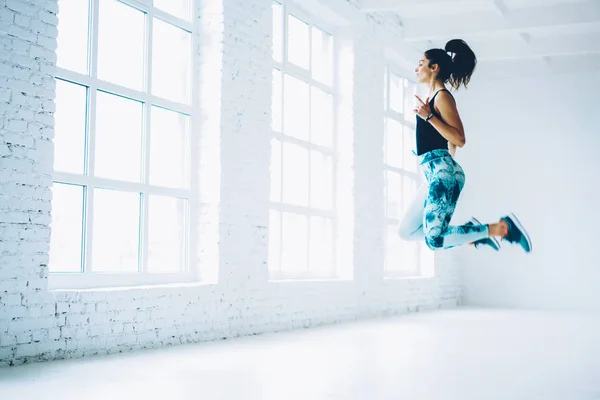 年轻女性在运动服跳跃做健美操锻炼为减肥和训练力量 运动员做跳跃的燃烧卡路里在普拉提锻炼享受活跃生活方式 — 图库照片
