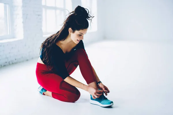 年轻健身女孩有休息时 在锻炼坐在运动鞋绑鞋带 运动员准备和检查鞋带在开始训练之前在健身房附近复制空间为 Advertisin — 图库照片