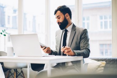 Kendine güvenen gurur CEO'su dijital dizüstü bilgisayarda ofis binası içinde çalışan muhasebe raporları okuma sakallı. Formal giyim modern netbook internet'e bağlı oturan erkek avukat giymiş