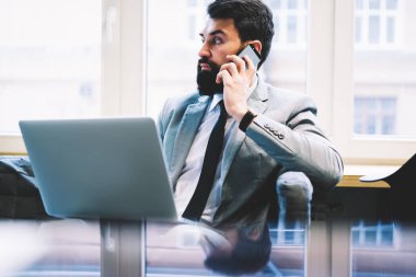 Çalışma projesi meslektaşı ile cep telefonunda Office iş metin kopyalama alanı alanı yakınında modern dizüstü bilgisayar ile otururken tartışırken sakallı emin ciddi icra müdürü