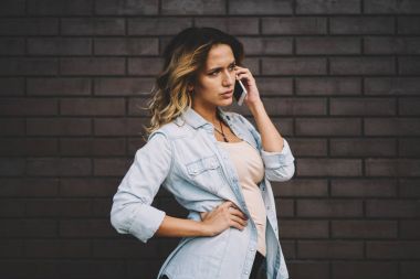 Güzel kadın blogger Sokağı'nda gezinme sırasında cep üzerinde uygulama kullanarak iletişim şık kıyafeti giymiş. Genç hippi kız ayakta duvara alan içerik için reklam ile sonraki