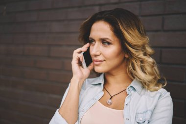 Boş zaman zaman modern cihaz ile şehir etrafında gezinme sırasında zevk güzel kadın blogger görüntüsünü kapatın. Kentsel ayarda ve telefonda konuşurken yürüyüş kıvırcık saçlı genç hippi kız