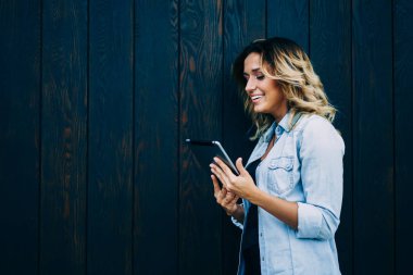 Genç başarılı blogger boş zaman zaman açık havada dokunmatik yüzey üzerinde web sitesi komik video izlerken zevk. İçeriğiniz için promosyon arka plan ile duvara sonraki duran neşeli sevimli kadın