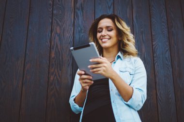 Olumlu çekici hippi kız dijital tablet sosyal ağ içinde takipçileri ile sohbet ederken bildirim kontrol. Serbest zaman sırasında kentsel ayarında teknolojisini kullanan genç gülümseyen kadın