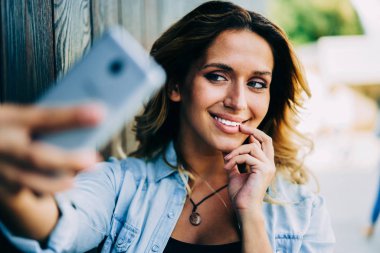 Smartphone kamerada kentsel ayarı ve alma selfie ücretsiz vakit genç çekici gülümseyen kadın. Sokağı'nda yürüyüş ve yapım profil resmi güncelleştirmek için fotoğraf çekici olumlu hipster kız