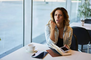 Genç düşünceli kadın blogger için kişisel web sitesi kapalı yayın yaratıcı fikirler düşünmeye. Ahşap masa kafede oturan başlangıç projesi hakkında durulması dalgın iş kadını