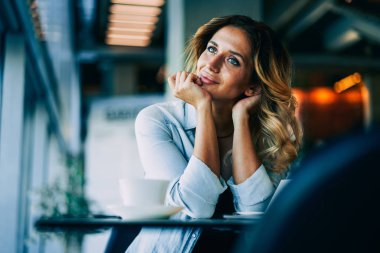 Genç mutlu hippi kız moda kıyafet kafede masada otururken hayal içinde giyinmiş. Muhteşem kadın blogger içerik kişisel web sitesi kapalı için yeni fikirler düşünmeye durulması