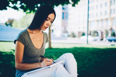 Genç esmer kız öğrenci, üniversite kampüsünün açık havada zaman harcama ise kurs yapmayı konsantre kroki çizim dalgın yetenekli hippi kız kitap zevk eğlence Şehir Parkı