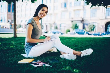 Gülümseyen rahat kıyafet capus zaman harcama üniversite için proje üzerinde genç kadın, çekici neşeli kız sırasında Çimenlikte oturan sketchbook çizim yapma ücretsiz bir süre için parkta üzerinde yaz gün