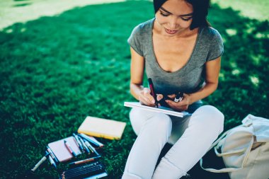 Gülümseyen kadın illüstrasyon olumlu genç kadının içinde sketchbook ile renkli kalemler çizim hobi serbest zaman üniversite kampüsü içinde oturan planlama yapmak için sabit kullanma