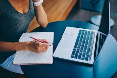 Uzak iş vakit içinde not etmek, öğrenci holding kalem online kurslar netbook üzerinde öğrenme sırasında notlar yapmak için hazırlanıyor bilgi yazma kafede olan kadın freelancer kırpılmış görüntü