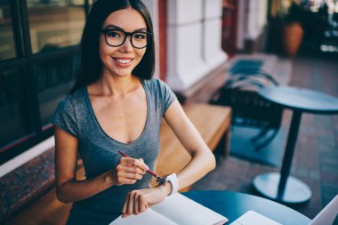 Başarılı kadın çevirmen smartwatch bildirim sırasında uzak iş Cafe, pozitif hippi kız kameraya bakarak iletilerini düzenleme için bilek bilgisayarla Eyewear kontrol portresi