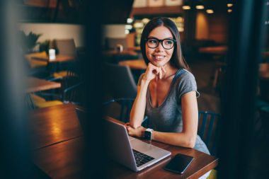 Çekici kadın serbest meslek hakkında fikir kafe Ardiles uzak iş için online rapor yapmak için netbook üzerinde USB'yi gözlük rüya gibi genç kadın çalışma projesi için gözlük düşünme