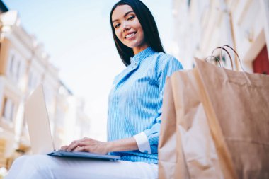 Yarım uzunluk portre rekreasyon açık havada sosyal ağ arkadaşlarıyla sohbet ederken zevk mutlu hippi kız. Ağ dosya indirme sırasında kameraya bakarak çok kadın kişi