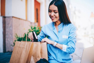Başarılı büyüleyici esmer işkadını defter kağıt paketi içine koyarak rahat kıyafetler giymiş görüntü kırpılmış. Boş zaman zaman açık havada oturma harcama genç güzel neşeli hippi kız