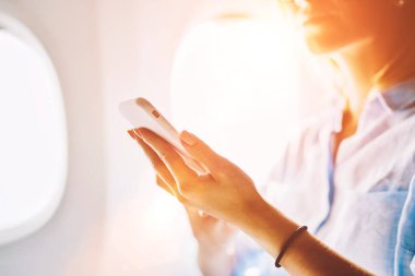 Genç beyaz kadın yolcu uçağın birinci sınıf konforlu hizmet zevk gemide Internet kablosuz bağlantı kullanarak kapatın. Kadın uçuş wifi ağ smartphone cep telefonu ile tarama