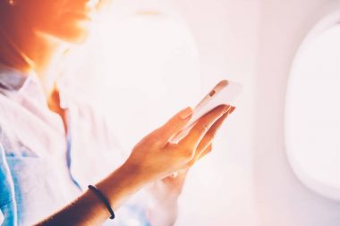 Genç beyaz kadın yolcu uçağın birinci sınıf konforlu hizmet zevk gemide Internet kablosuz bağlantı kullanarak kapatın. Kadın uçuş wifi ağ smartphone cep telefonu ile tarama