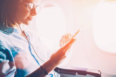 Genç kadın meloman mobil müzik ve Aksesuar, kadın kulaklık smartphone üzerinden müzik keyfi uçağın tahta üzerinde eğlenceli kullanarak birinci sınıf kabinde uçuş sırasında en sevdiğiniz şarkıları dinleme