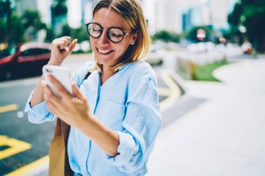 Mutlu erkek rendy Eyewear Müjdemi isterim telefon tutarak ve şehir sokak, şehir merkezindeki gülümseyen açık havada yürüyüş başarı kutluyor duygusal hippi kız yürüyüş e-posta alma ile çok memnun