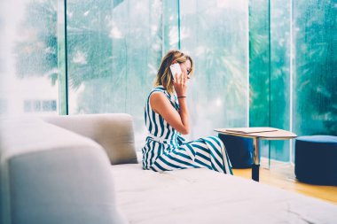 Modern daire yeni çağdaş tasarım sipariş yolu ile modern ev iç rahat koltukta oturan dijital smartphone aygıt hakkında konuşmayı şık beyaz kadın sahibi yan görünüm