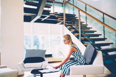 Modern iç evde için fikirler ile skeçler üzerinde çalışan genç yaratıcı tasarımcı lüks konut ile çağdaş mobilya dizüstü bilgisayar kullanarak. Evde çalışan başarılı iş kadını