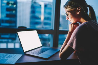 Gözlük gülümseyen kadın Tasarımcısı reklam akşam saat evde harcama dizüstü bilgisayarda boş kopya alanı ekranda izlerken ile memnun. Kadın alay içeriği modern netbook üzerinde okuma