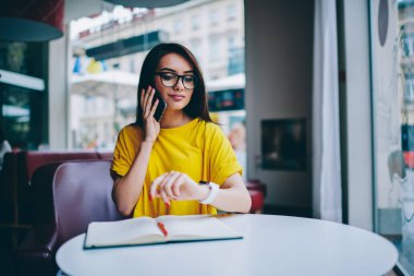 Kol saati ve bekleyen meslektaşım kafede ararken smartphone telefon konuşma sırasında eserin problem çözme gözlük çekici işkadını. Telefonla konuşurken kadın Yöneticisi