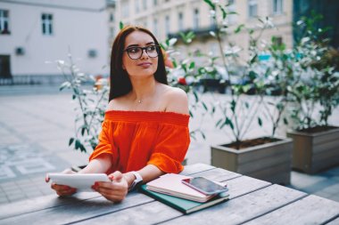 Dijital tablet aygıtı elinde tutan ve kendi iş şey dokunun proje açık havada şehir merkezinde oturan için yeni yaratıcı fikirler üzerinde düşünme optik gözlükler çekici genç girişimci