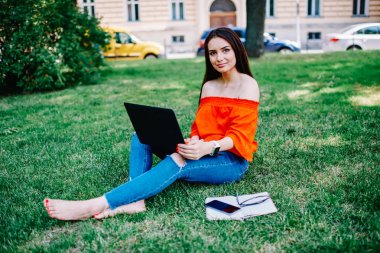 Tam uzunlukta portre çekici mutlu esmer kadının uzaktan çalışarak dizüstü bilgisayarda kablosuz internet'e bağlı. Gadget'ı kullanarak öğrenme sırasında kameraya bakarak şirin olumlu kız öğrenci
