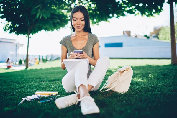 Vrolijke Jonge Vrouw Zittend Groen Gras Huiswerk Doen Chatten Met — Stockfoto