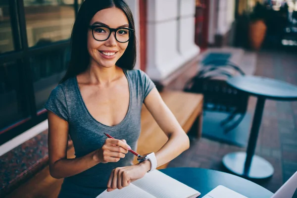 Başarılı kadın çevirmen smartwatch bildirim sırasında uzak iş Cafe, pozitif hippi kız kameraya bakarak iletilerini düzenleme için bilek bilgisayarla Eyewear kontrol portresi