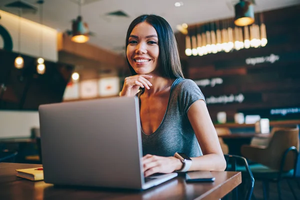 微笑的成功自由职业者的肖像享受自由的时间表和远程工作的时间在咖啡馆 开朗的女人使用无线连接实现工作过程的更新在上网本上的应用 — 图库照片