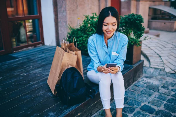 年轻迷人开朗的黑发妇女在蓝色衬衫上检查通知的智能手机连接到互联网 迷人的成功女性的人看有趣的视频网站上的现代手机 — 图库照片