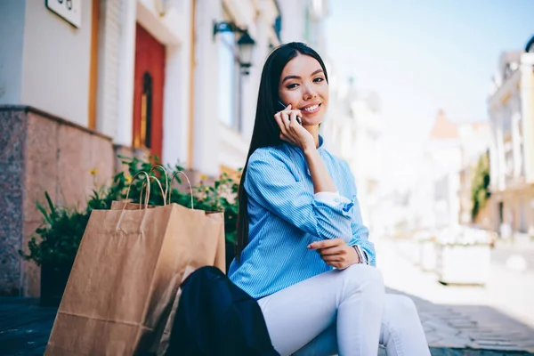 半长的肖像美丽的微笑的女性博客与朋友通过手机 而坐在户外交谈 年轻可爱的黑发亚洲妇女花费自由时间与现代设备 — 图库照片