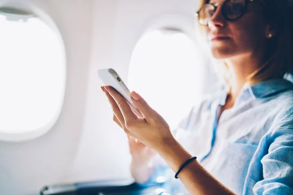 在飞机上使用互联网无线连接 关闭了年轻的白种女性乘客 享受头等舱的舒适服务 在智能手机上浏览飞行 Wifi 网络的妇女 — 图库照片