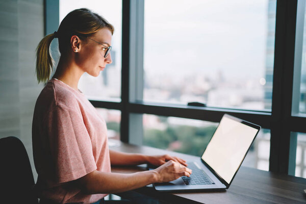 Боковой вид концентрированной клавиатуры копирайтера для публикации в интернете на популярном сайте с использованием высокоскоростного 4G-подключения для загрузки во время работы на цифровом ноутбуке
