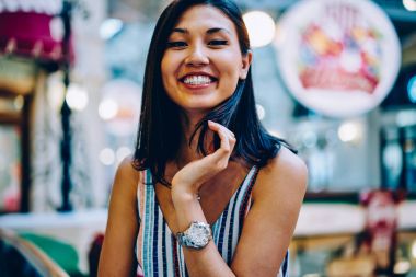 Neşeli güzel Asyalı kız kameraya, arka plan bulanık kapalı üzerinde zevk boş duran gülümseyen şirin esmer genç kadın arıyorum mutlu duygu portresi yarım uzunlukta tarih seçici odak