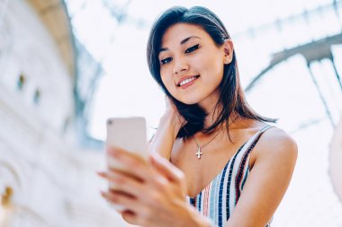 Internet bağlantısı ile sosyal ağ mobil, çekici Asyalı kız modern smartphone uygulama yükleme sayfasında web tarama Son Haberler okuma olumlu genç kadını tatmin