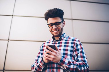 Neşeli erkek öğrenci gözlük bloglama açık havada duran ise e-posta arkadaş fotoğraf alma ekose gömlekli hipster adam gülümseyen takipçileri ile mobil sohbet yoluyla sosyal ağlar