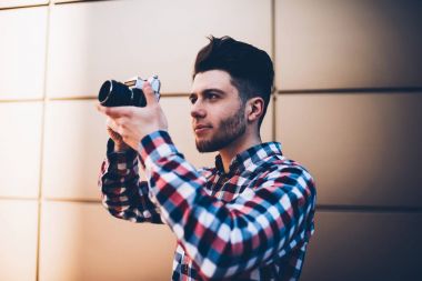 Profesyonel genç erkek fotoğraf lens odak eski kamerada çekim çalışmalarına, hipster adam açık havada duran görüntüleri yapım vintage kullanýlýyor fotoğraf düşkün konsantre