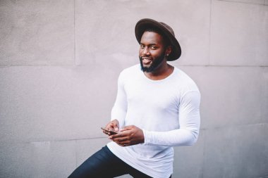 Afro-Amerikan yakışıklı genç moda şapka bloglama smartphone ve kopya alan arka plan, kameraya bakarak hipster esmer adam manifatura mesaj portresi poz ile sosyal ağlar