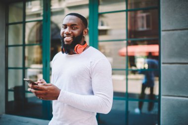 Sahte kamera süre sosyal ağlar üzerinden smartphone içinde fotoğraf gönderme kopya alanı göz yukarı ile Beyaz gömlekli neşeli Afrikalı-Amerikalı adam varoluş portresi. Cep telefonu kullanarak gülümseyen hipster adam